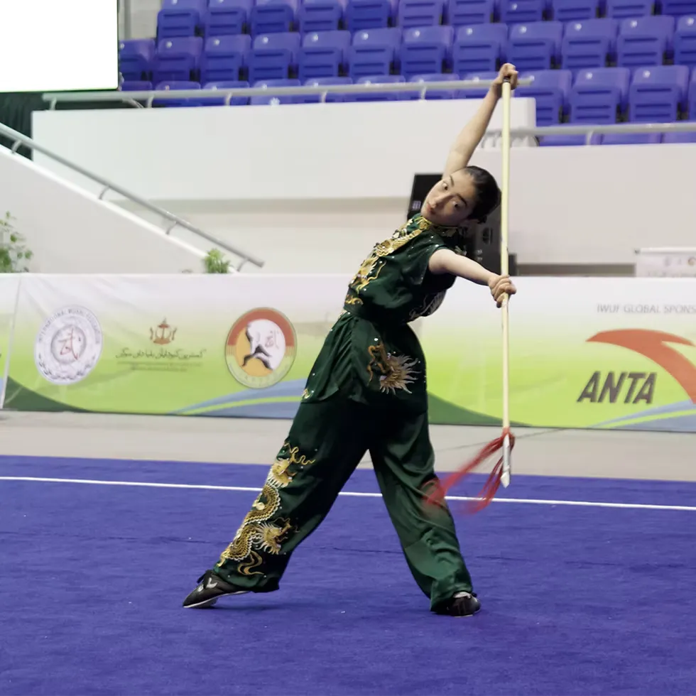 Annie Harris performing with staff at the 2024 World Junior Wushu Championships
