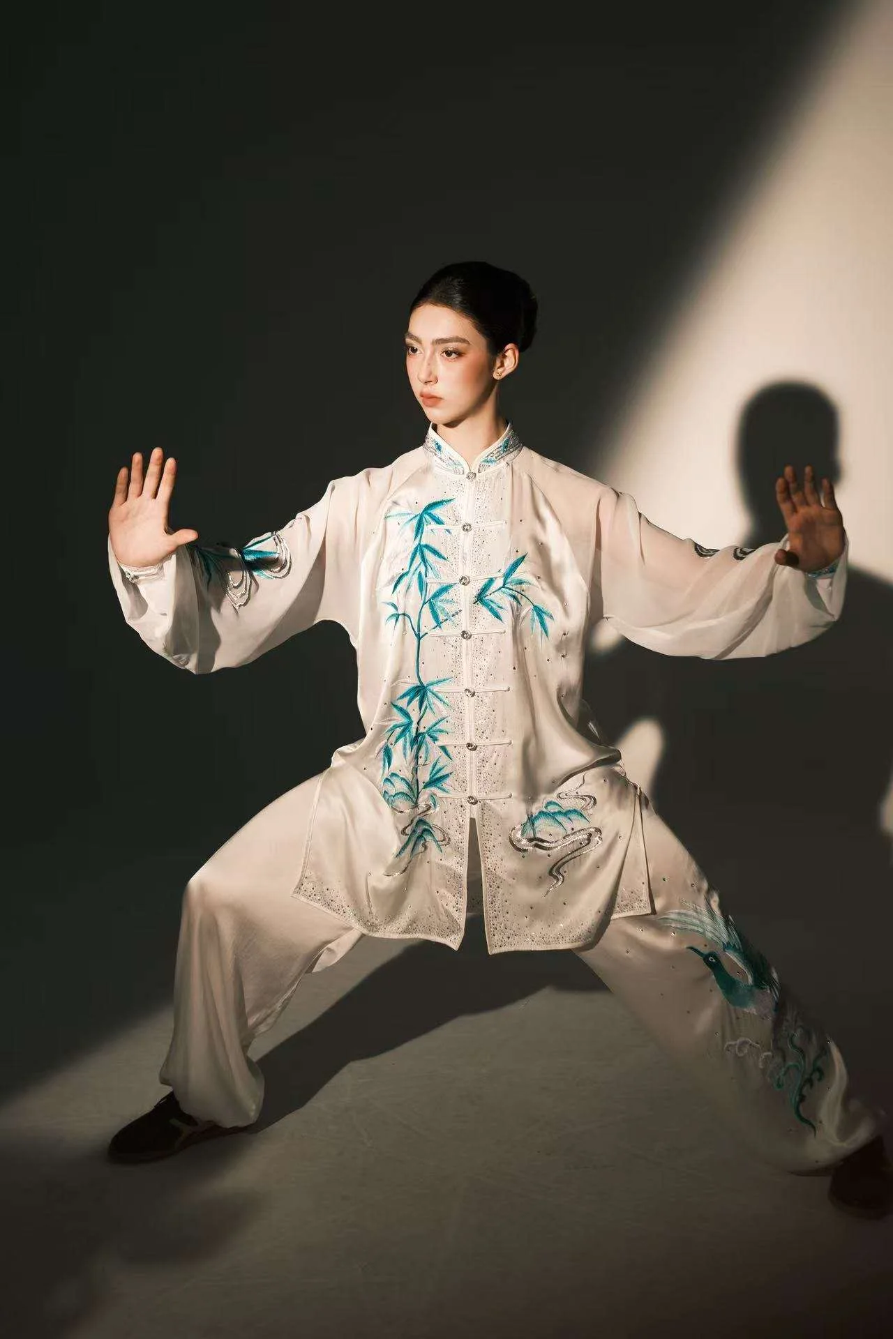 Annie Harris — wushu editorial, horse stance, teal bamboo embroidered uniform, dark background